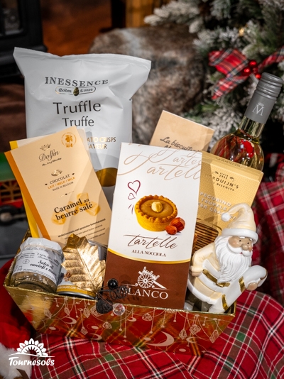 Panier garni avec friandises, vin et décorations de Noël.